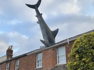 The Headington Shark sculpture protruding headfirst from the roof of a red brick house in Oxford.