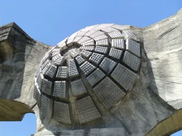 Textured dome detail of the Monument to the Revolution of the People of Moslavina against a blue sky.