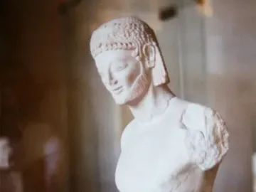 Fragmentary marble head and upper body of the Rampin Rider with an archaic smile, beard, and detailed hair.