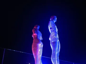 Ali and Nino sculpture illuminated in blue and magenta at night