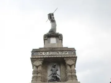 Cuauhtémoc Monument with tiered stone reliefs and a statue holding a spear-like object on top