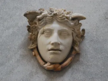 Medusa Rondanini marble face with curly hair-like elements, downcast eyes, and visible cracks in the stone.