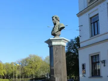 Pushkin bust on a tall column behind a decorative iron fence