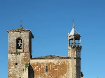 Francisco Pizarro equestrian statue partly visible behind palm fronds, with a stone church in the background.