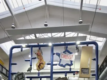 Entropa sculpture with a blue framework suspending irregular shapes in a spacious room.
