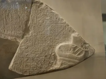 Stele of the Vultures fragment showing rows of carved cuneiform and a small animal relief in the lower right