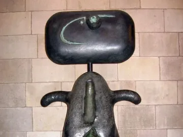 Femme by Joan Miró, a dark abstract sculpture with a rounded head, curved arm-like forms, and a green teardrop shape on the front.