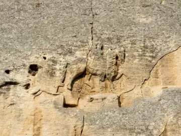 Madara Rider rock relief showing a horseman on horseback, a dog running ahead, and a faint fallen figure below.