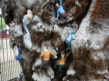 Detail of the Elfin Oak showing colorful sculpted figures embedded in a weathered tree trunk.