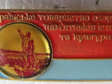 Commemorative badge featuring a circular emblem with the Lenin Monument in Zaporizhzhia and Cyrillic text on a red and light blue background.