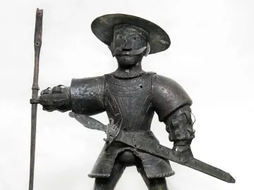 Old Thomas weather vane figure in armor with a wide-brimmed hat, mustache, staff, and sword.