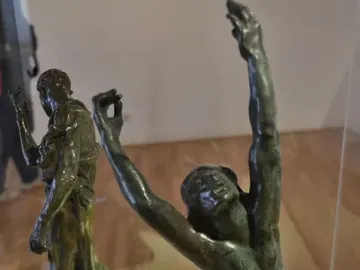 The Prodigal Son bronze statue of a kneeling nude man with arms raised and head thrown back, with another robed figure behind him.