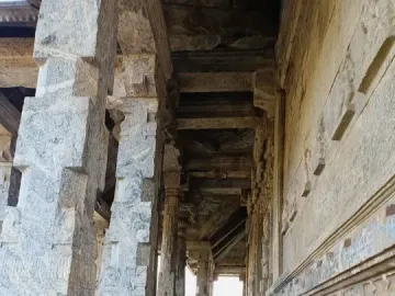 A long stone corridor with massive carved pillars and bright light at the far end.