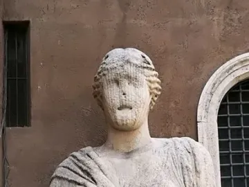Madama Lucrezia stone bust with draped figure and coiled hair against a brick wall
