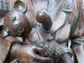 Bronze figure in Trains to Life – Trains to Death holding a stitched toy bear