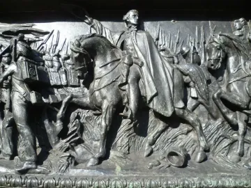 Bronze relief panel on the Duke of Wellington statue showing a mounted figure and soldiers in a battle scene.