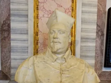 Bust of Cardinal Scipione Borghese in cream-colored marble, shown wearing a cap and buttoned garment with a mustache and goatee.