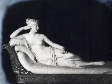 Venus Victrix, a white marble sculpture of a reclining female figure on an ornate chaise lounge, holding an object in one hand.