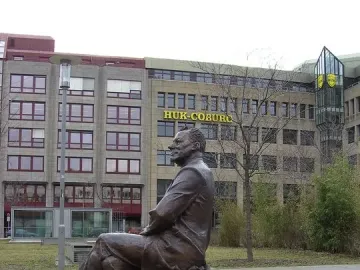 Willy Brandt Memorial bronze statue of a seated man on a long bench outdoors.