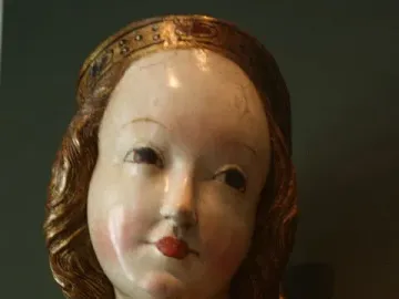 Close-up of the crowned Madonna of Krużlowa with painted face and colorful robes.