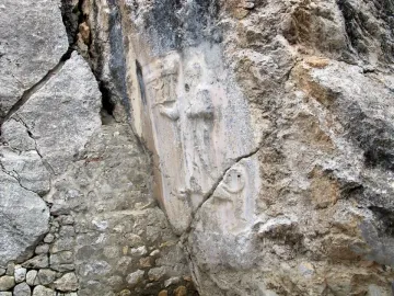 Bas-relief carvings on the rock face at Yazılıkaya, with stylized figures carved into a smoother section of stone.