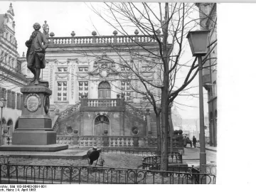 Goethe Monument stands on a tall pedestal in front of an ornate building in Leipzig.