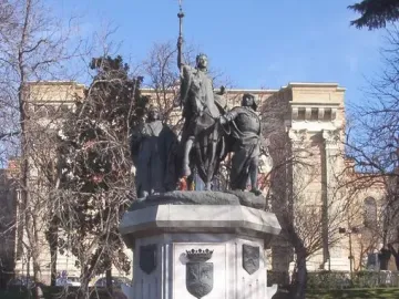 Monument to Isabella of Castile showing a bronze equestrian statue on an ornate marble pedestal in a shallow pool.