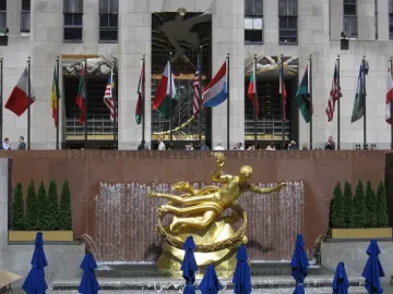 Prometheus sculpture at Rockefeller Center, a golden reclining figure above a fountain with flags overhead.