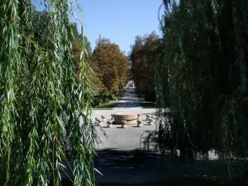 The Table of Silence with its circular stone table and surrounding seats along a tree-lined gravel path.