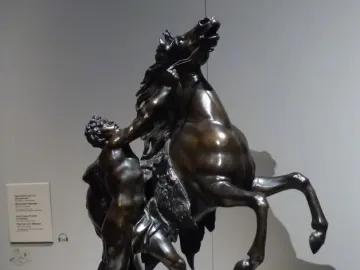 Marly Horses, a dark bronze sculpture of a muscular man restraining a rearing horse.