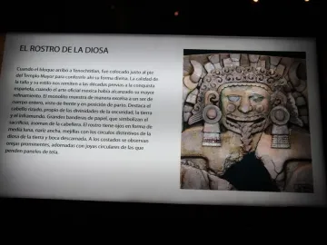 Museum display board showing the Tlaltecuhtli Monolith with Spanish text and a carved stone face with an open mouth, tongue, and elaborate headdress.