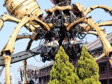 La Princesse mechanical spider with four operators seated inside its central body against a blue sky.