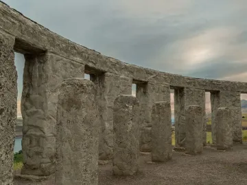 Maryhill Stonehenge, with rough concrete pillars and lintels arranged in a partial circle overlooking rolling hills and water.