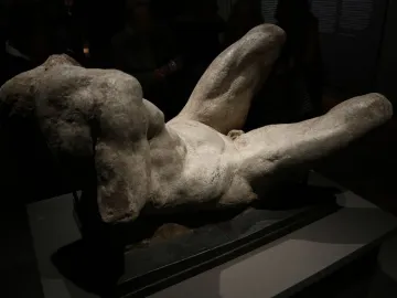 Reclining River God sculpture with a textured torso and legs on a dark base.