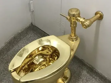 America gold toilet in a room corner with a speckled grey floor