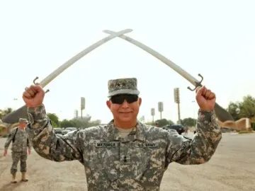 The Victory Arch with crossed swords towers in the background while a uniformed soldier stands in the foreground holding smaller swords.