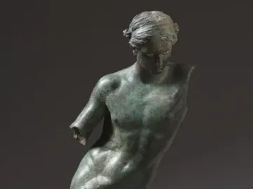 The Cleveland Apollo bronze statue with a green patina, standing on a simple base against a dark background.