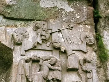 Externsteine relief showing figures around a central cross carved into a weathered rock face.
