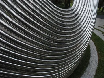 Close-up of the Infinite Wave sculpture’s reflective metallic tubes curving together outdoors.