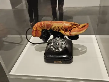 Salvador Dalí’s Lobster Telephone with a red lobster resting on a black rotary telephone inside a display case.