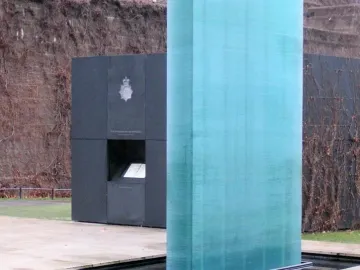 The National Police Memorial with a tall translucent teal column beside a dark memorial structure.
