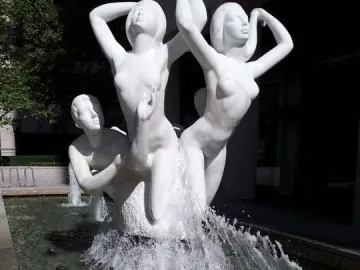 The Quest sculpture, a white marble fountain with nude figures in dynamic poses and water jets around the basin.