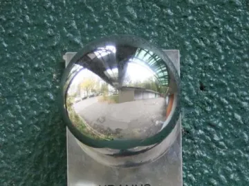 Reflective Uranus sphere mounted on a metal plaque against a dark green wall.