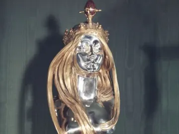 Nature sculpture by Alfons Mucha, showing a silver-faced woman\'s bust with flowing golden hair and a golden crown.