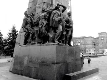 The base of the Lenin Monument in Zaporizhzhia, showing sculpted figures on a granite pedestal in a public square.