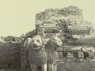 Lion Capital of Ashoka sculpture with two lions and a partially visible third lion head atop a decorated capital with wheels.