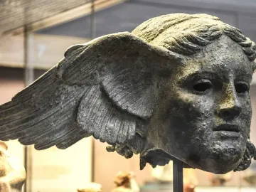 Bronze head of Hypnos with feathered wings at the temples and a weathered patina.