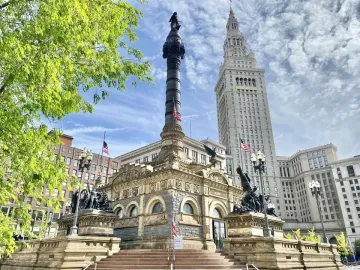 Soldiers\' and Sailors\' Monument in Cleveland with a tall granite shaft, surrounding sculptural figures, and American flags.