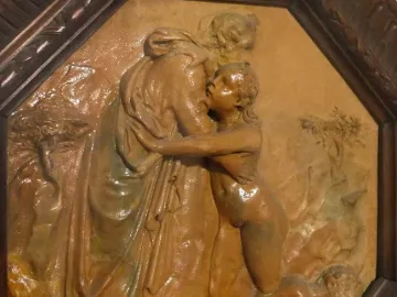 Donatello’s Creation of Eve relief in a dark octagonal frame, showing a robed figure embracing a nude figure above a reclining body.