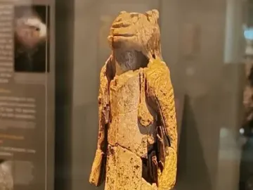 Fragmented Lion-man sculpture with an animal head and rough light-colored surface on a display base.